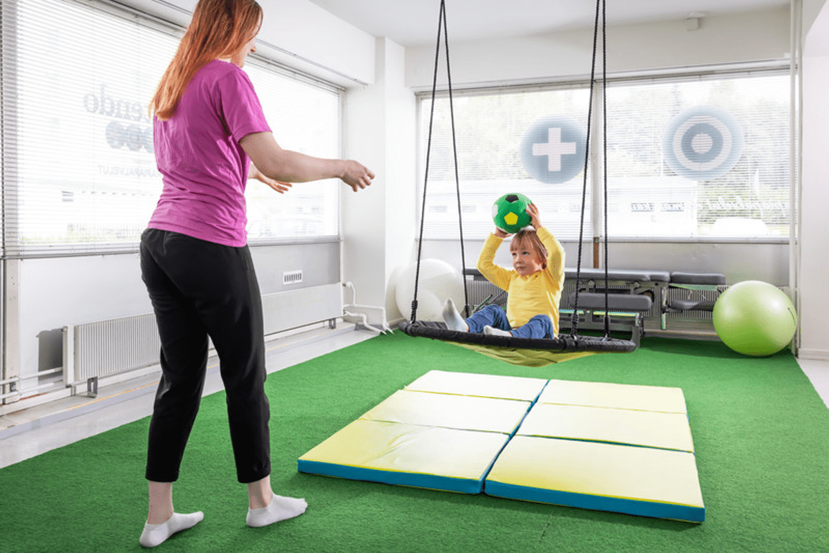 Terapeutti tekee lapsen kanssa koordinatioharjoitusta Attendo Terapian toimipisteessä