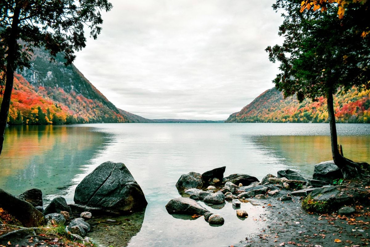 A tranquil lake reflects colorful autumn mountains.
