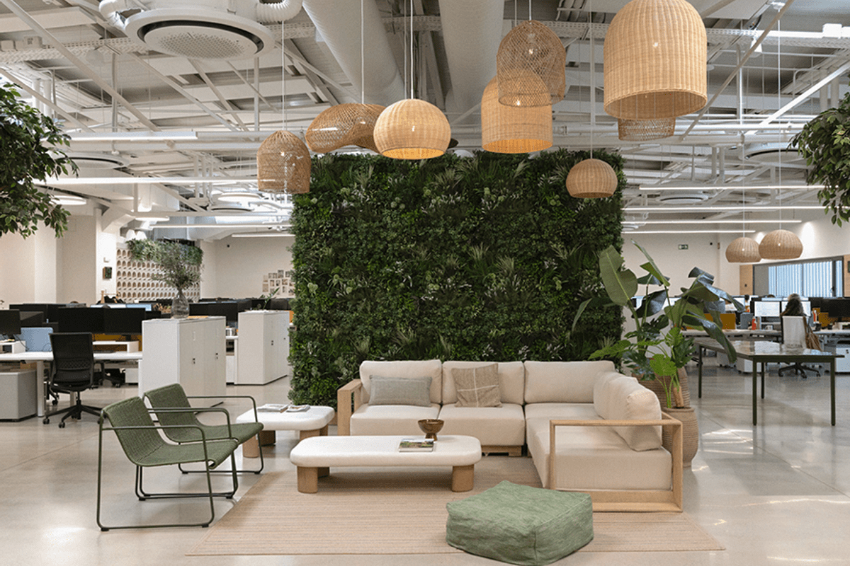 Open-plan Kave Home office with lounge seating area, plants, and hanging woven lamps