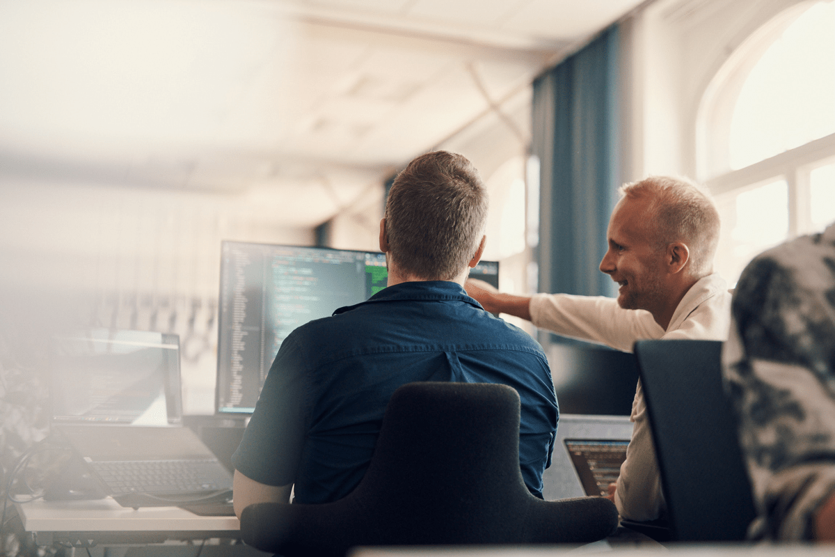 Two men pointing at a computer screen