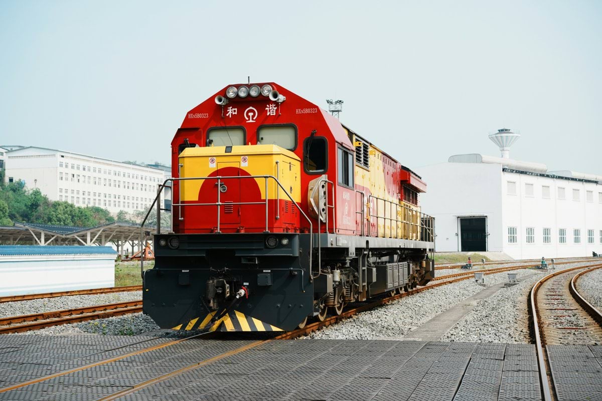 A red and yellow train sits on railroad tracks.