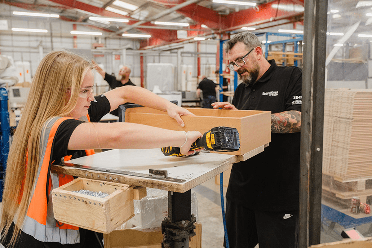 Young girl in safety gear and a man with tools in a manufacturing hub