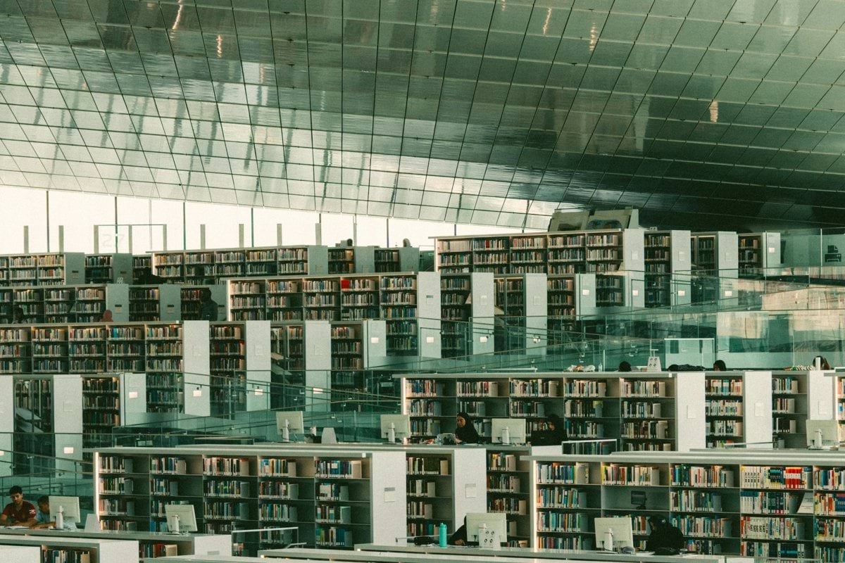 Modern library with expansive bookshelves and seating areas.