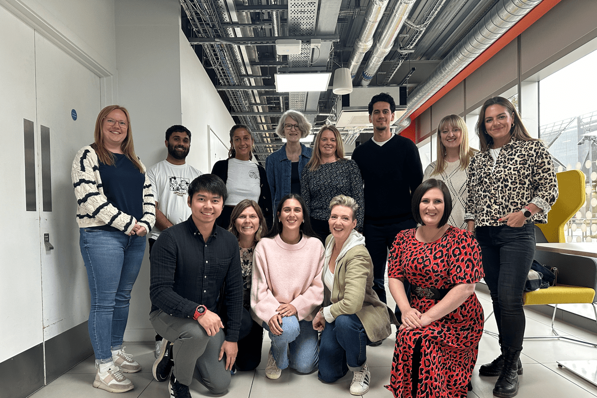 Staff photo of 13 members of UKAD's EDI Working Party together. 5 along the front are on one knee with the others standing behind them