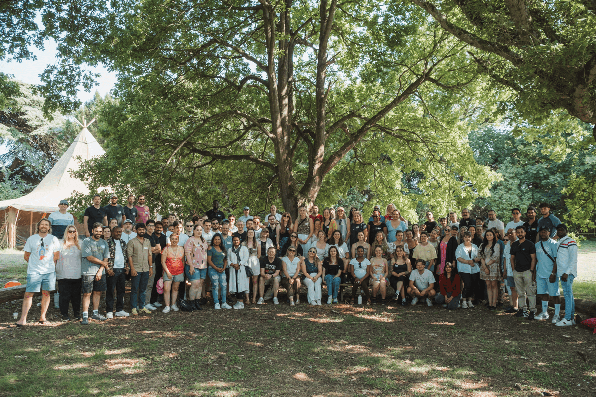 group photo of the smol team in a field with trees and tent in the background