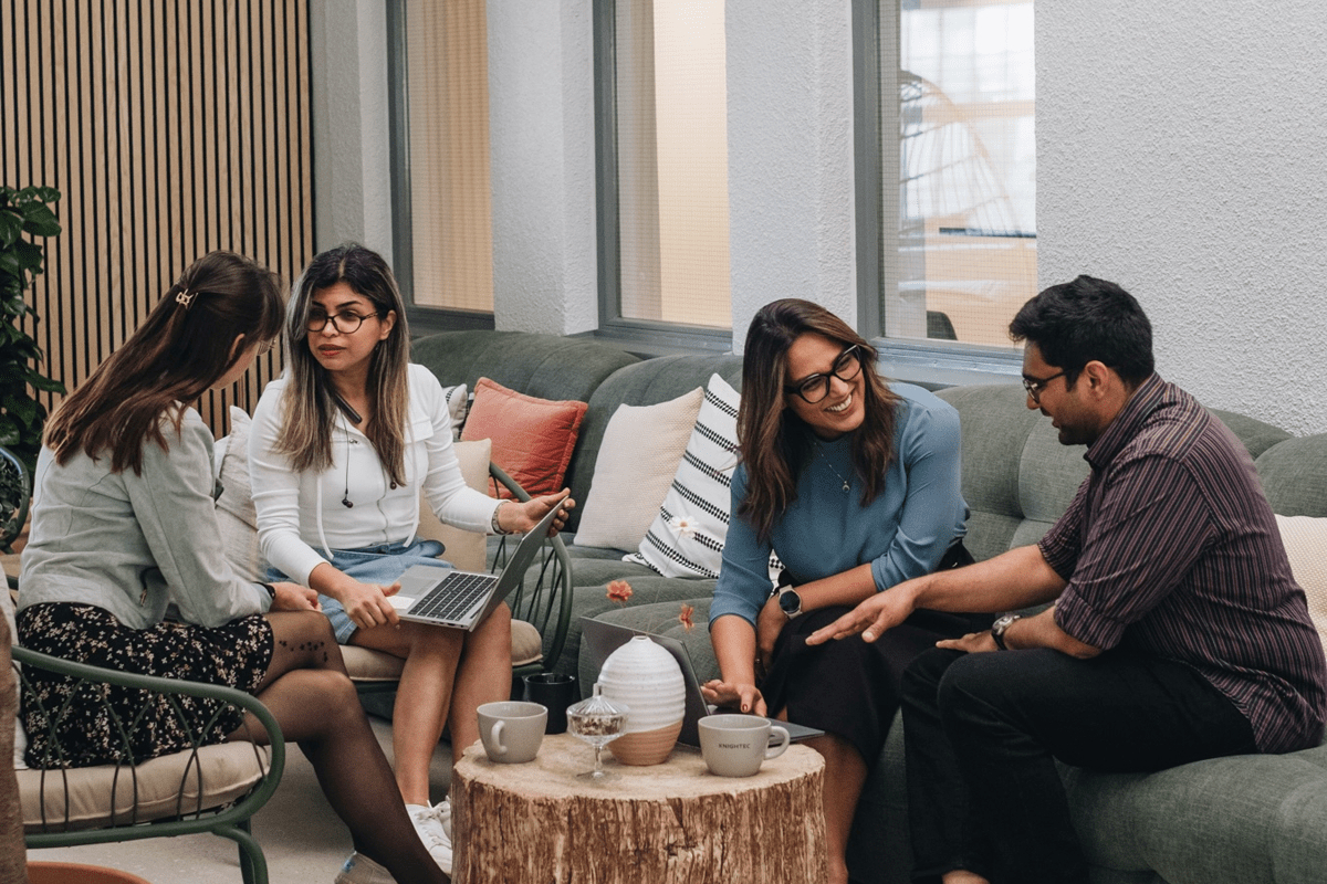 Four people sitting in a lounge area, talking around a table
