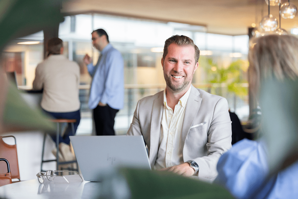 Medarbetare leende framför datorn pratar med en kollega