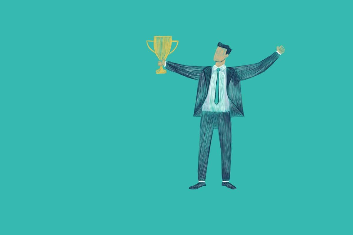 Man in suit holding a trophy with arms raised