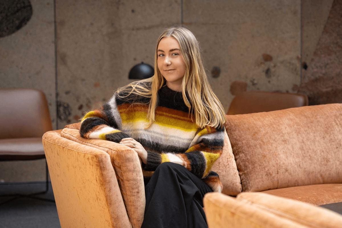 en kvinna med randig tröja sitter i en sammetssoffa