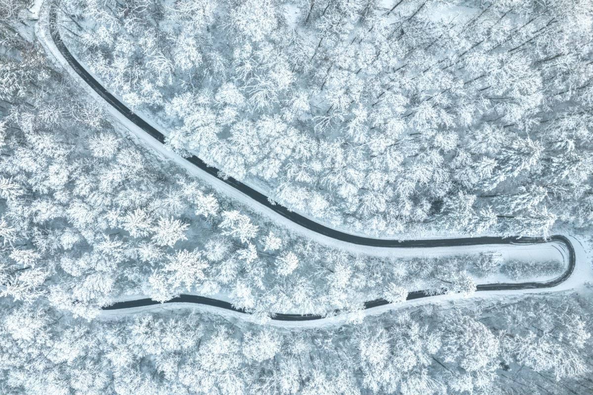 a winding road in the middle of a snow covered forest