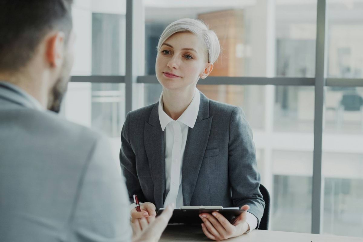 Woman in suit interviews man at desk
