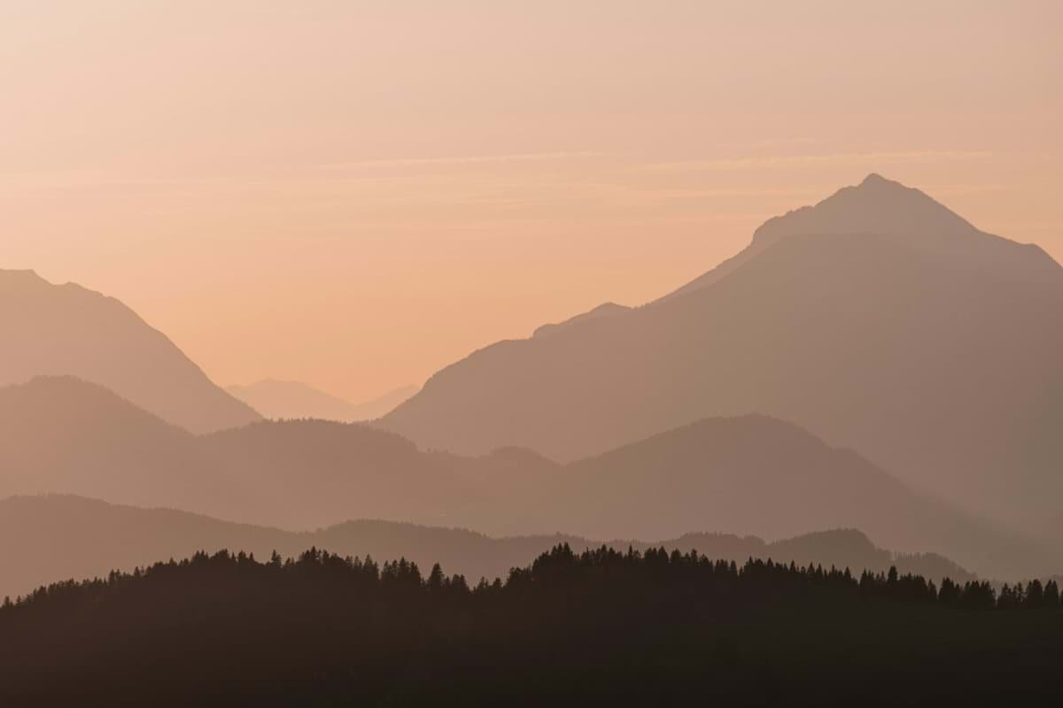 Layered mountain silhouettes against a soft orange sky