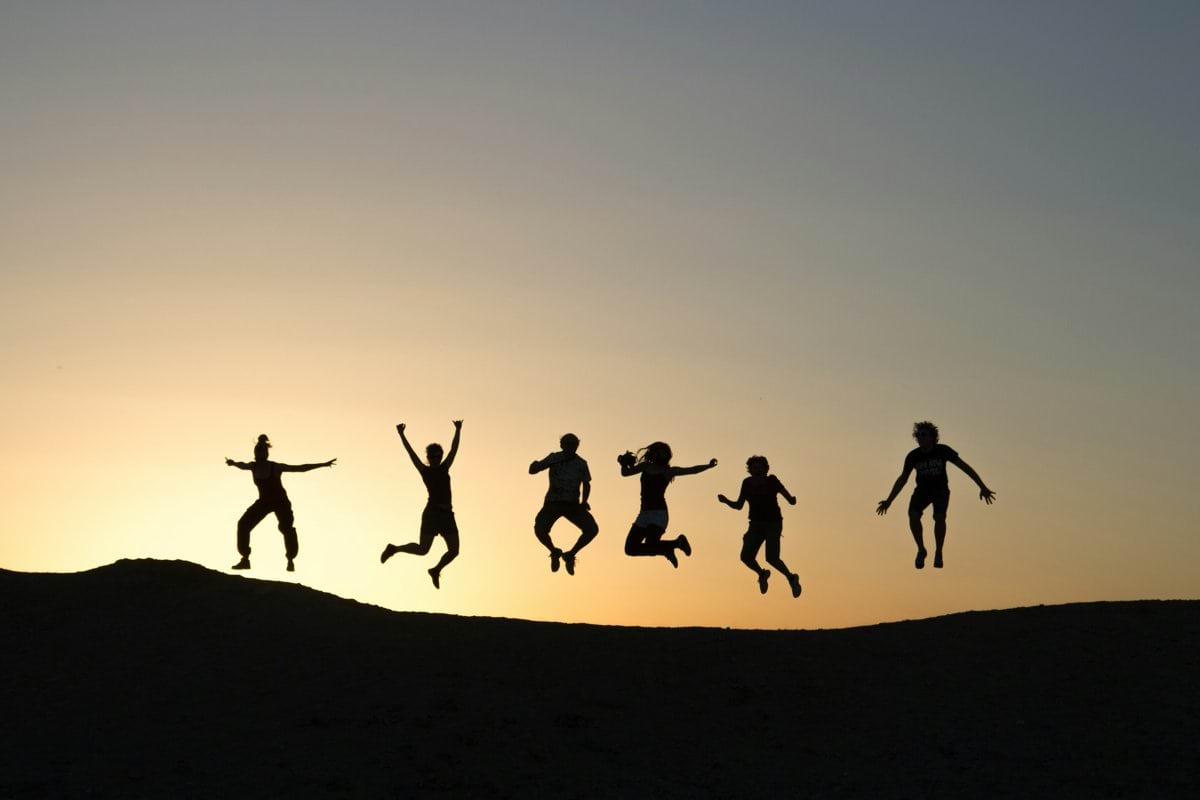 six silhouette of people jumping during sunrise