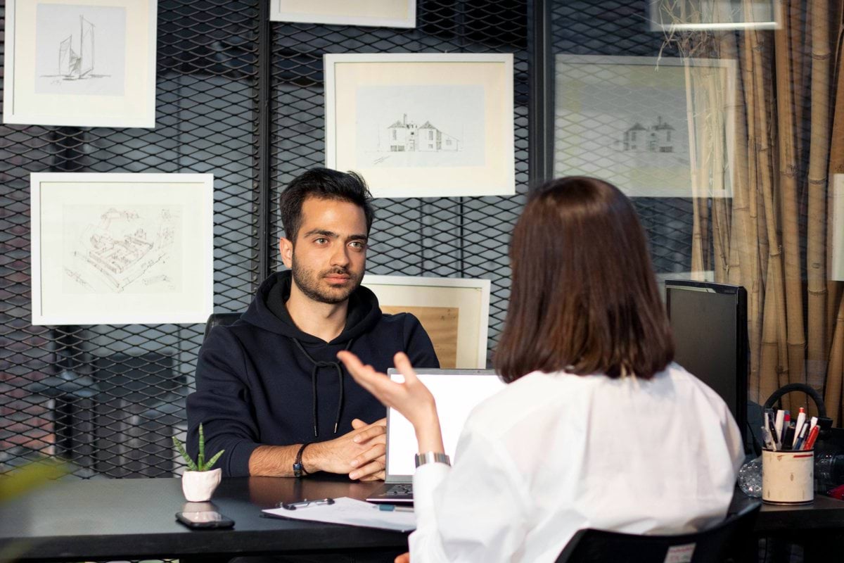 a man sitting at a desk talking to a woman