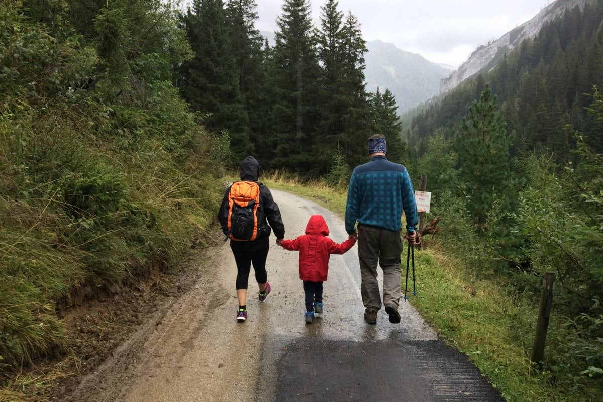 man, woman, and child walking together along dirt road