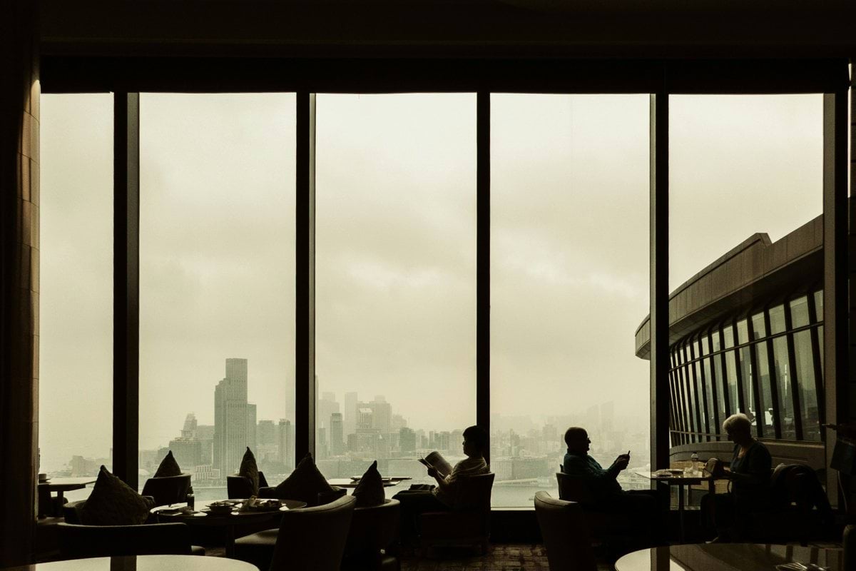 People sit near a window overlooking a cityscape.