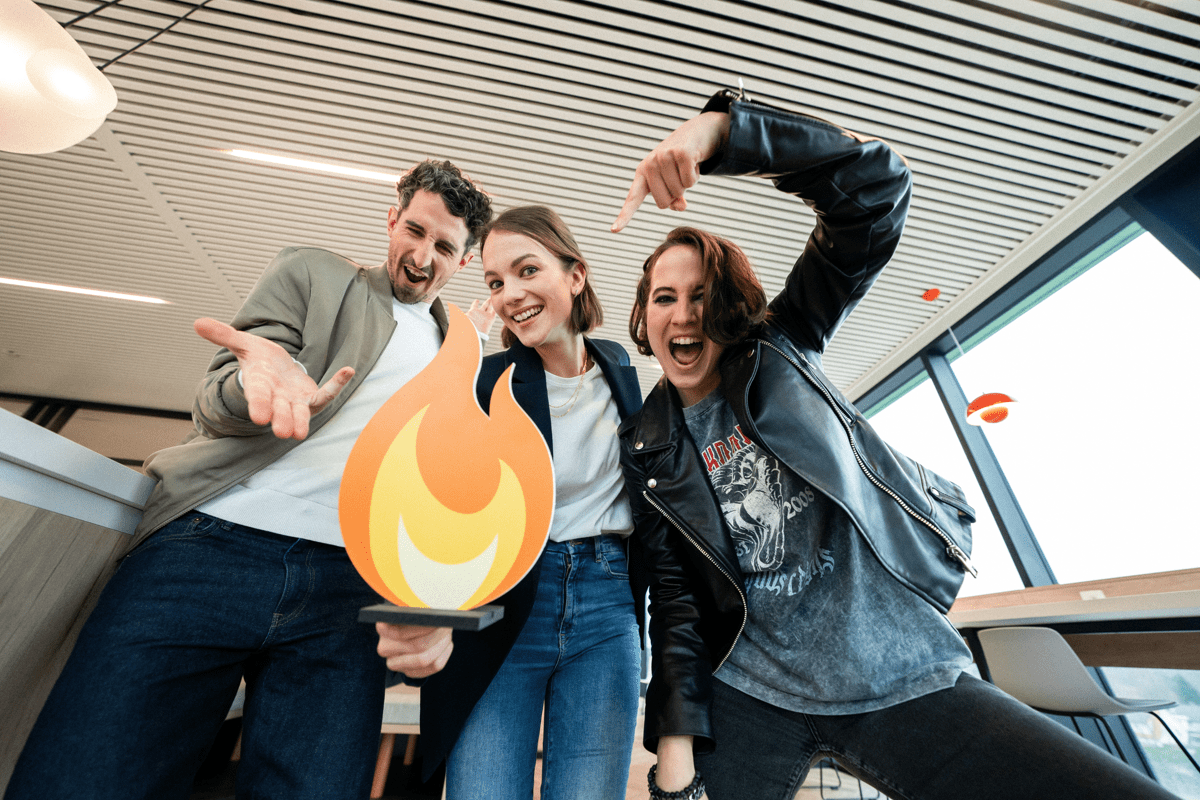 Three young people smiling at the camera with an animated flame