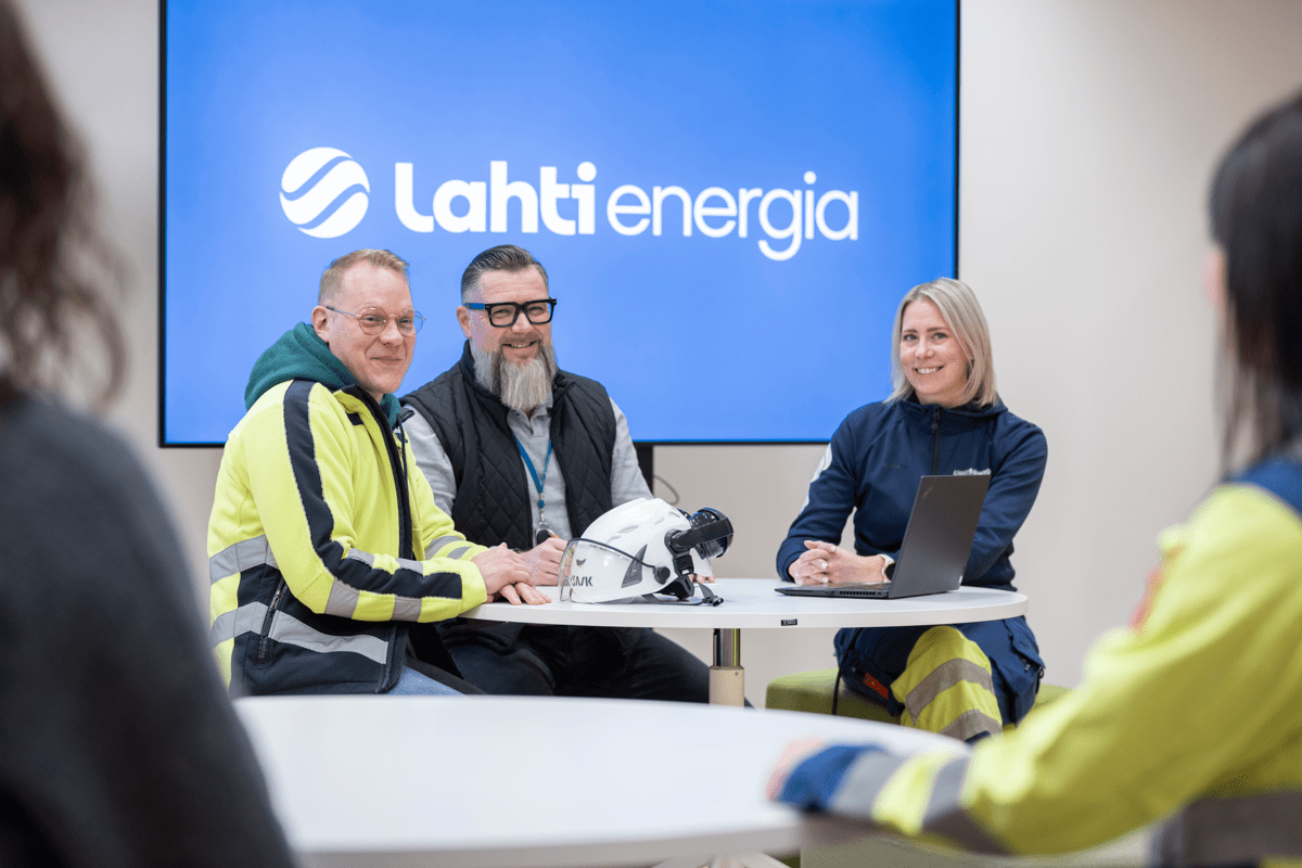 Kolme työntekijää istuu pöydän ääressä.