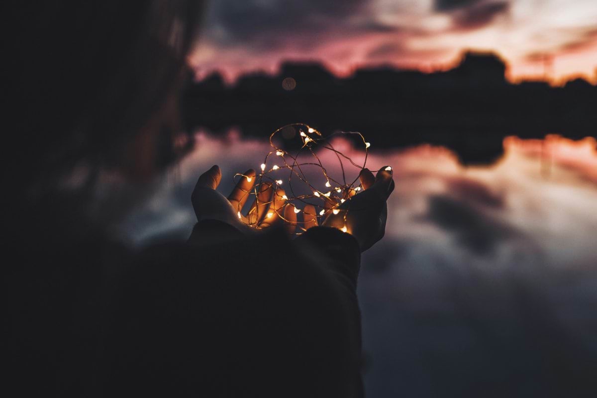 person holding turned on string lights during nighttime