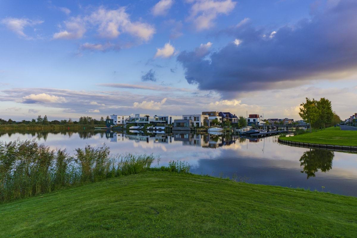 green grass field near body of water under blue sky during daytime