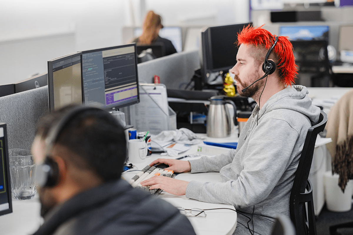 Man with red hair and headset on in a call centre