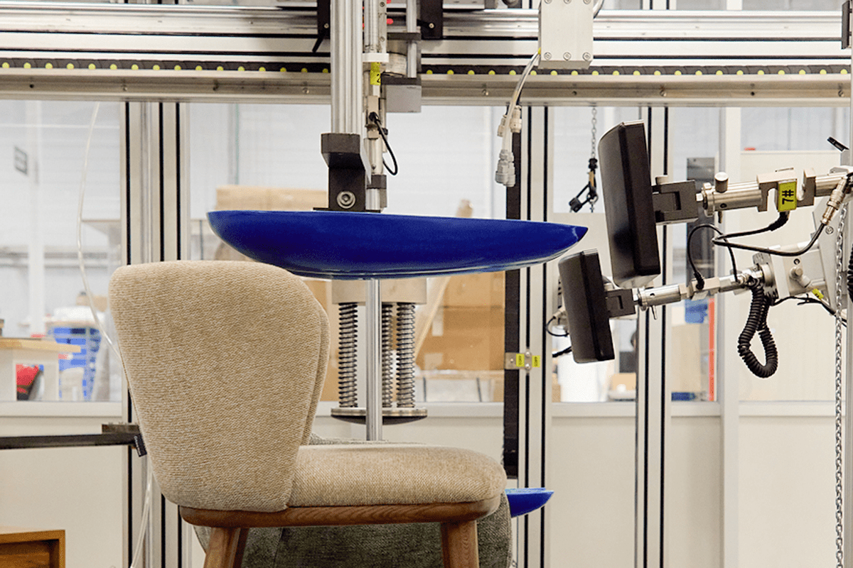 Chair undergoing automated seat durability testing through repeated use simulations