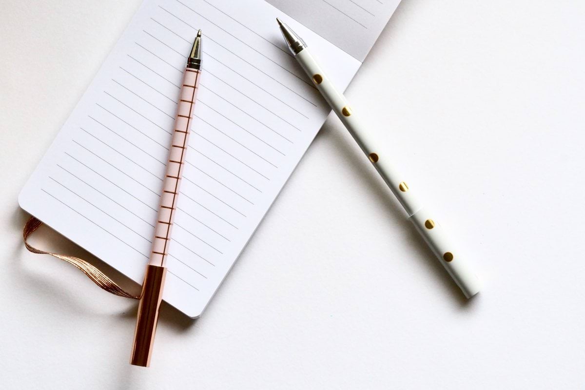 two white and beige pens on white paper