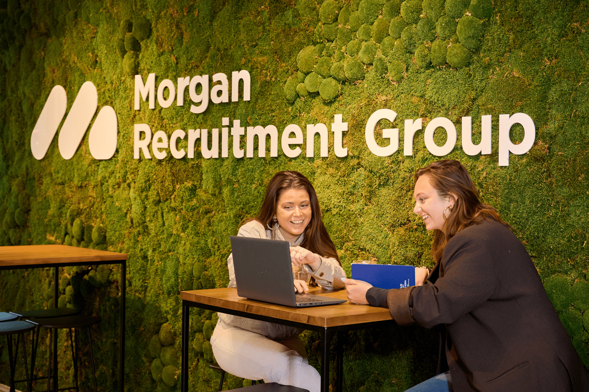 De marketing manager en corporate recruiter zijn samen in overleg op locatie amsterdam bij de logo muur