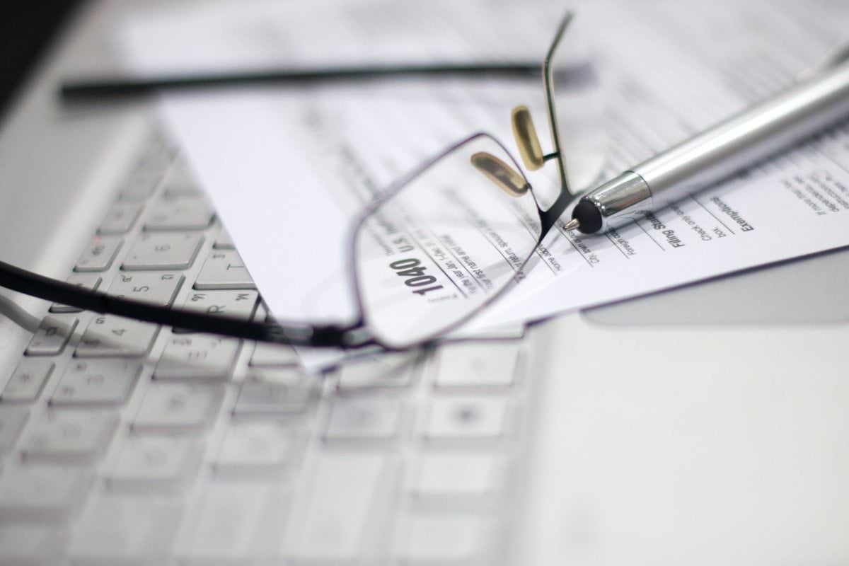 Glasses and pen on tax form and laptop.