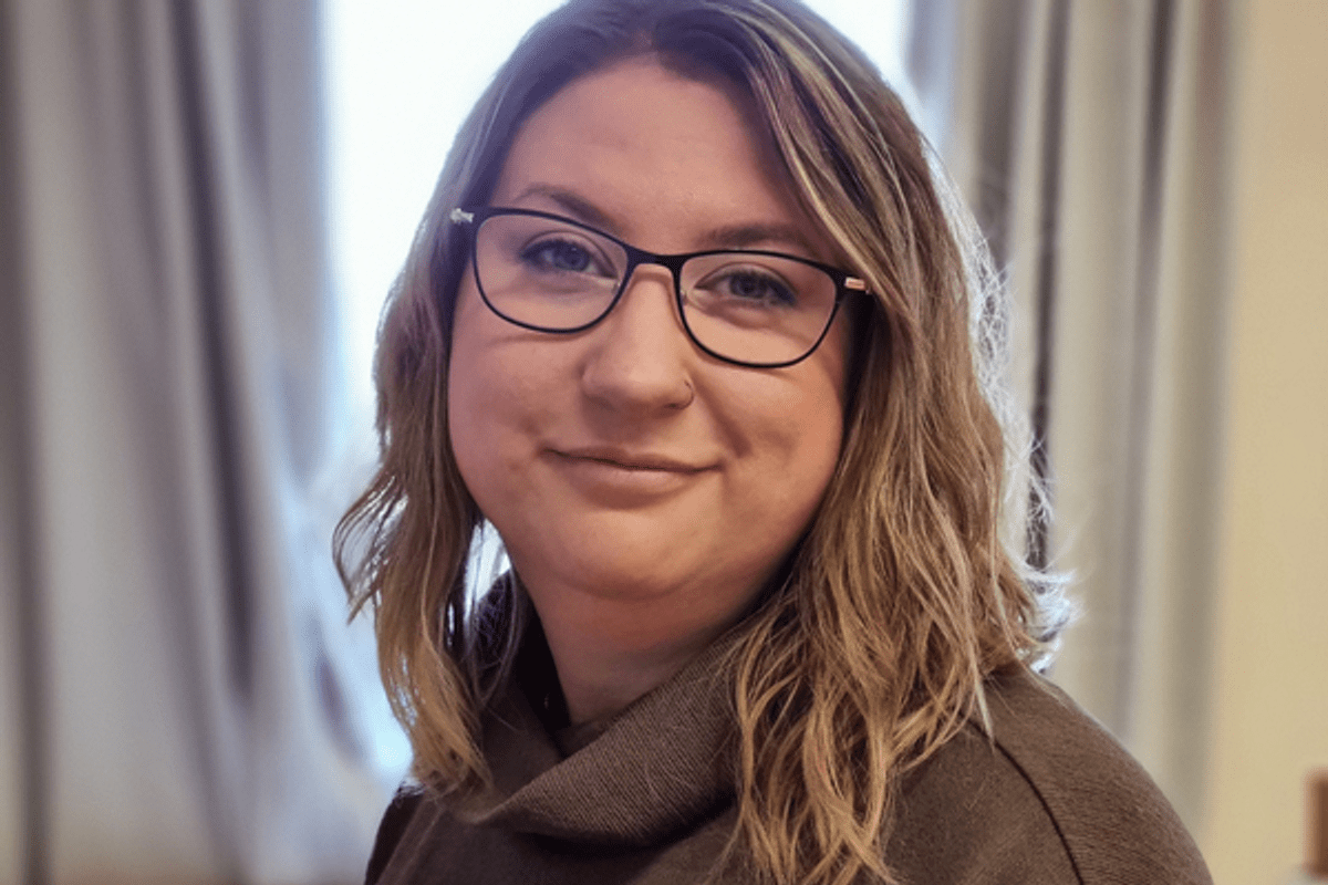 Porträtt av kvinna med hår ner till axlarna och glasögon.