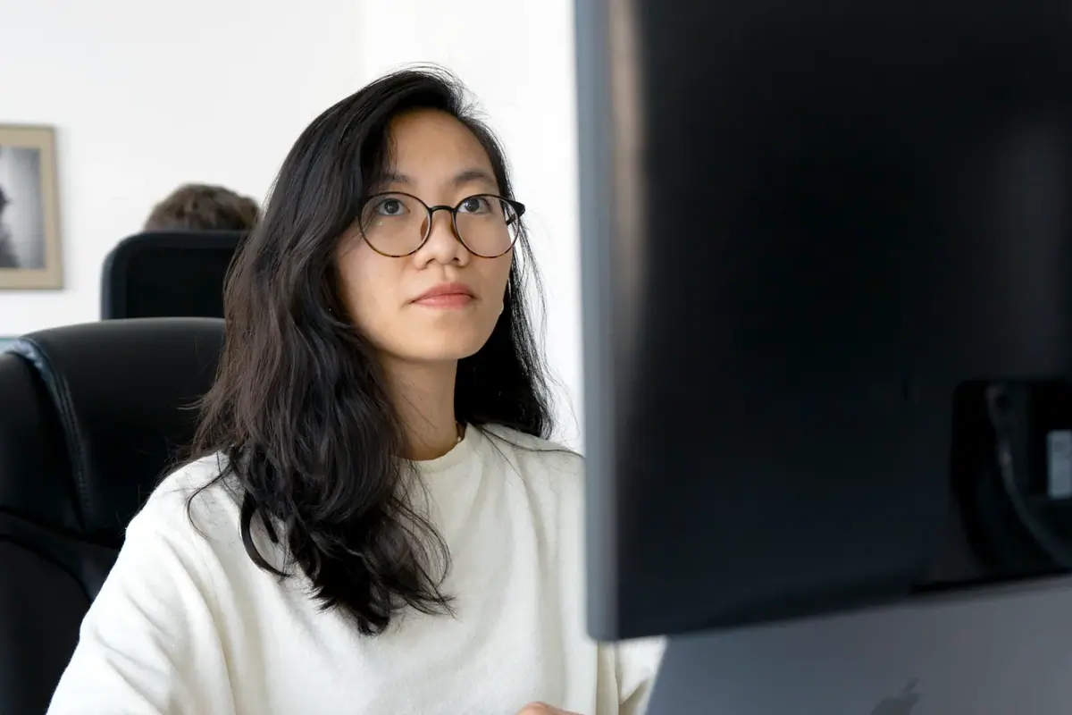 A colleague sitting at a desk and working at a computer in an office.