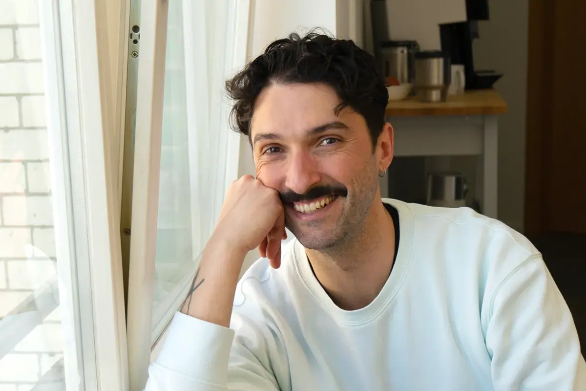A colleague smiling while sitting at a desk in a bright office.