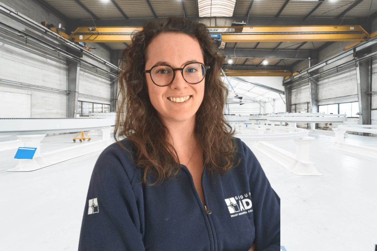 Portrait de Célia STOPA, collaboratrice du Groupe ADF, devant un atelier de fabrication industrielle