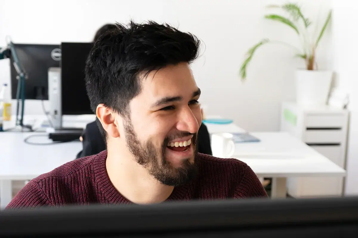 A colleague smiling while working at a computer in an office.