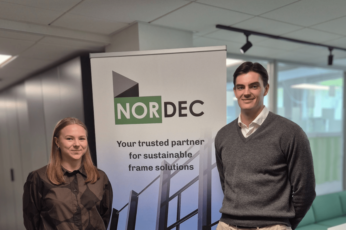 Nordec summer design trainees standing in front of a roll-up at an office