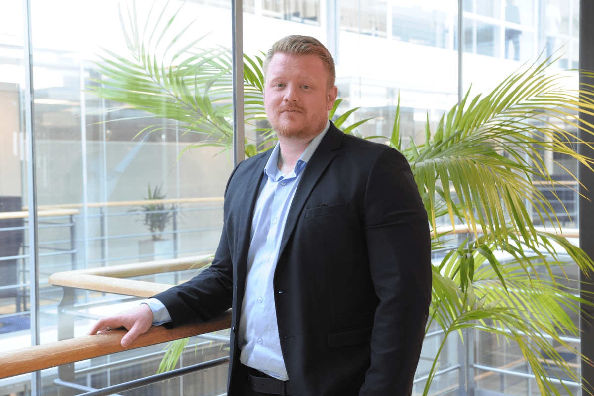 Man i kostym står i kontorsmiljö.