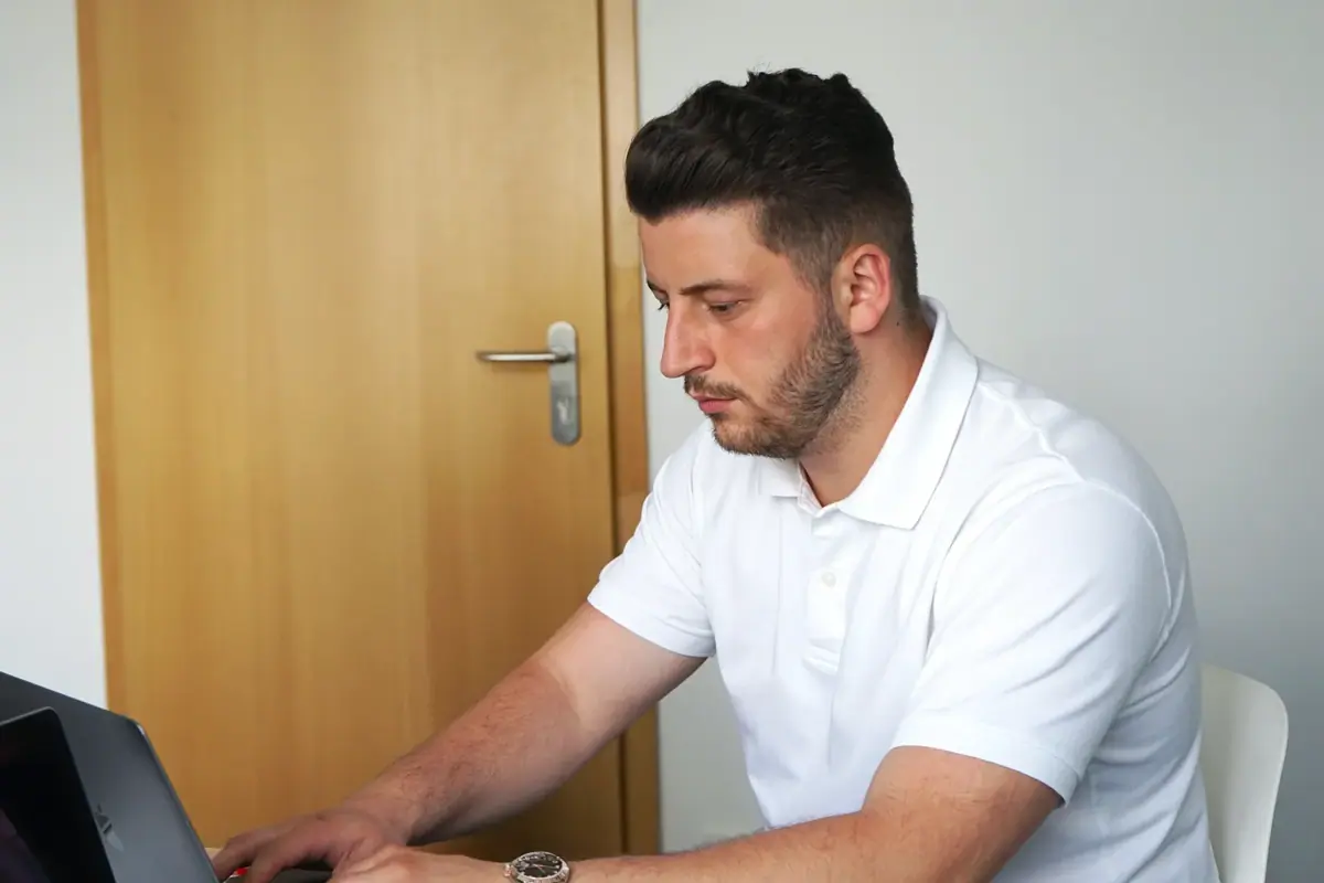 A colleague sitting at a desk and working on a laptop in an office.