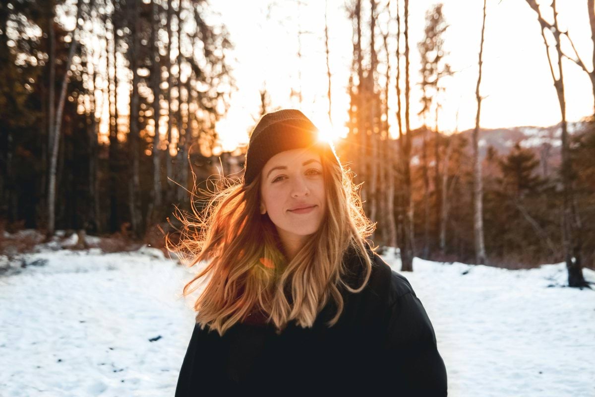 woman in black jacket and knit cap standing on snow covered ground during daytime
