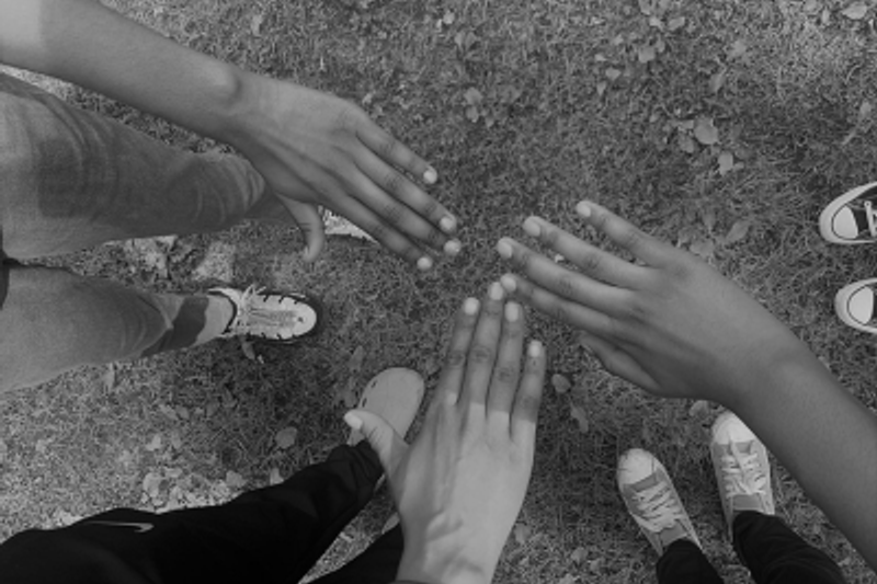 Three hands reaching together in a circle