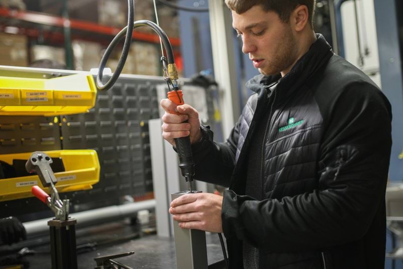 man in black jacket holding black and yellow hand tool