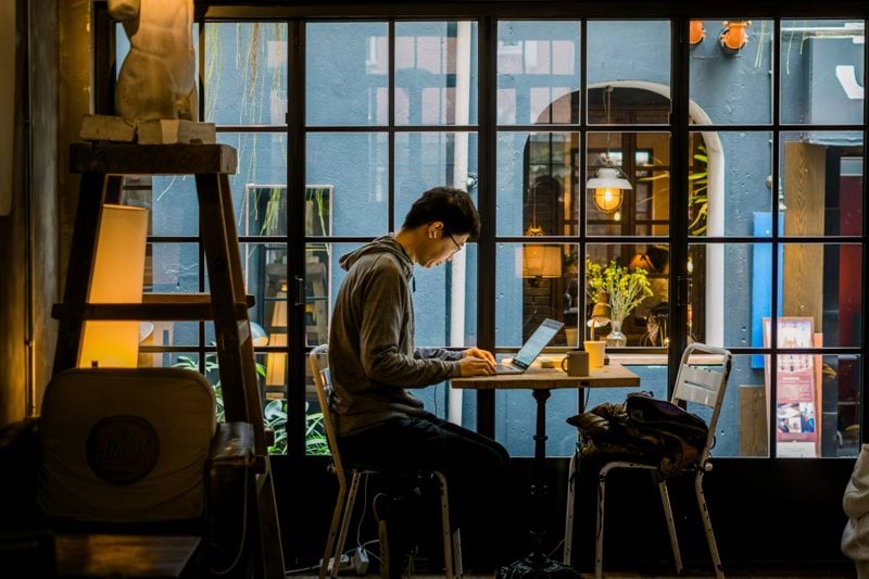 Man working on laptop in a cafe by the window