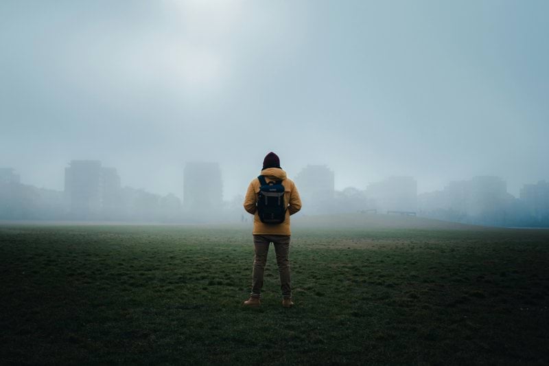 woman in black shirt and black shorts standing on green grass field during foggy weather
