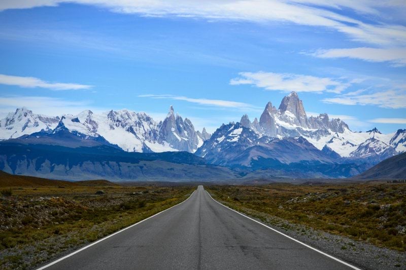 gray concrete road near snow covered mountain during daytime