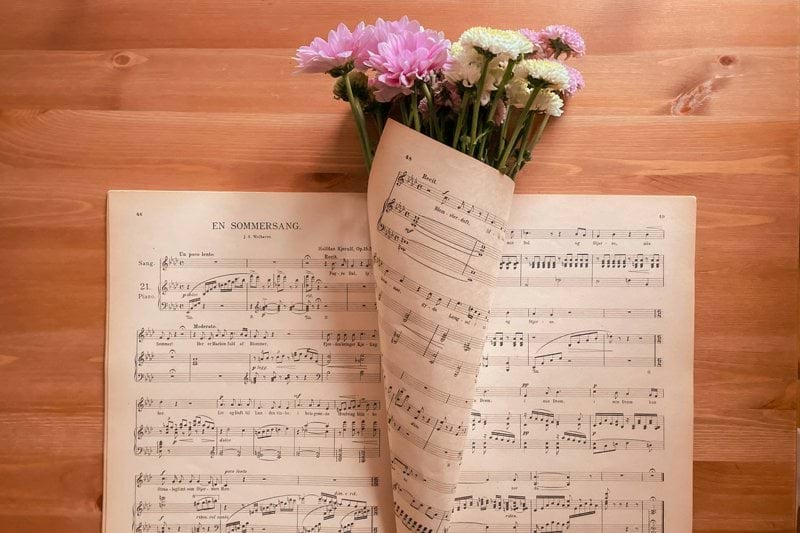 a sheet of music with flowers on top of it