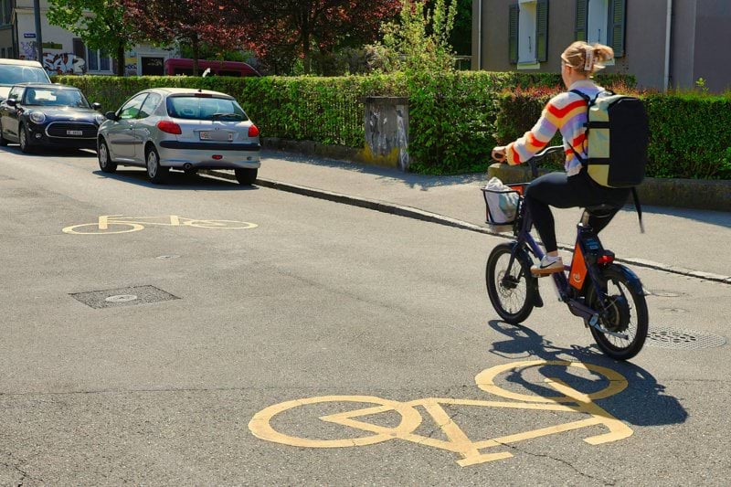 Woman riding electric bike on street with bike lane markings