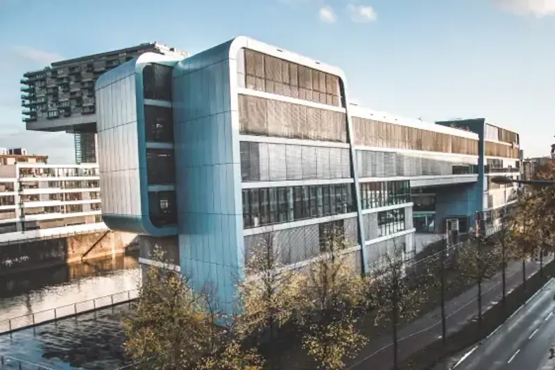 Microsoft building in Cologne with glass and metal facade alongside a tree-lined street