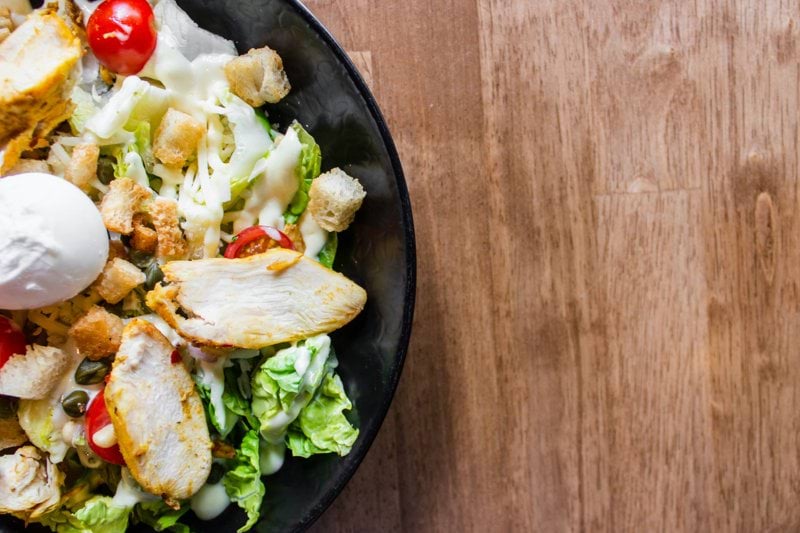 meat with vegetables and sliced tomatoes in black bowl