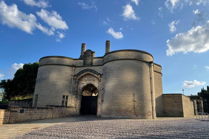 a stone building with a gate and a sky background