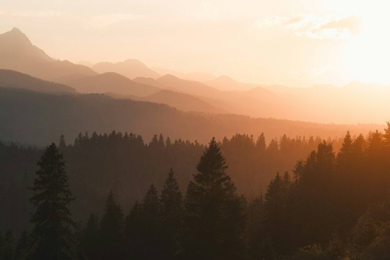 the sun is setting over the mountains in the distance