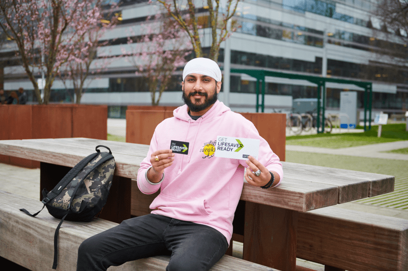 Young man signing up to the stem cell register, holding his swabs and leaflet